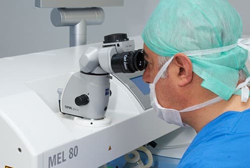 Augenarzt in OP-Kleidung am Lasersystem